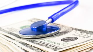 A stethoscope placed on top of a stack of money